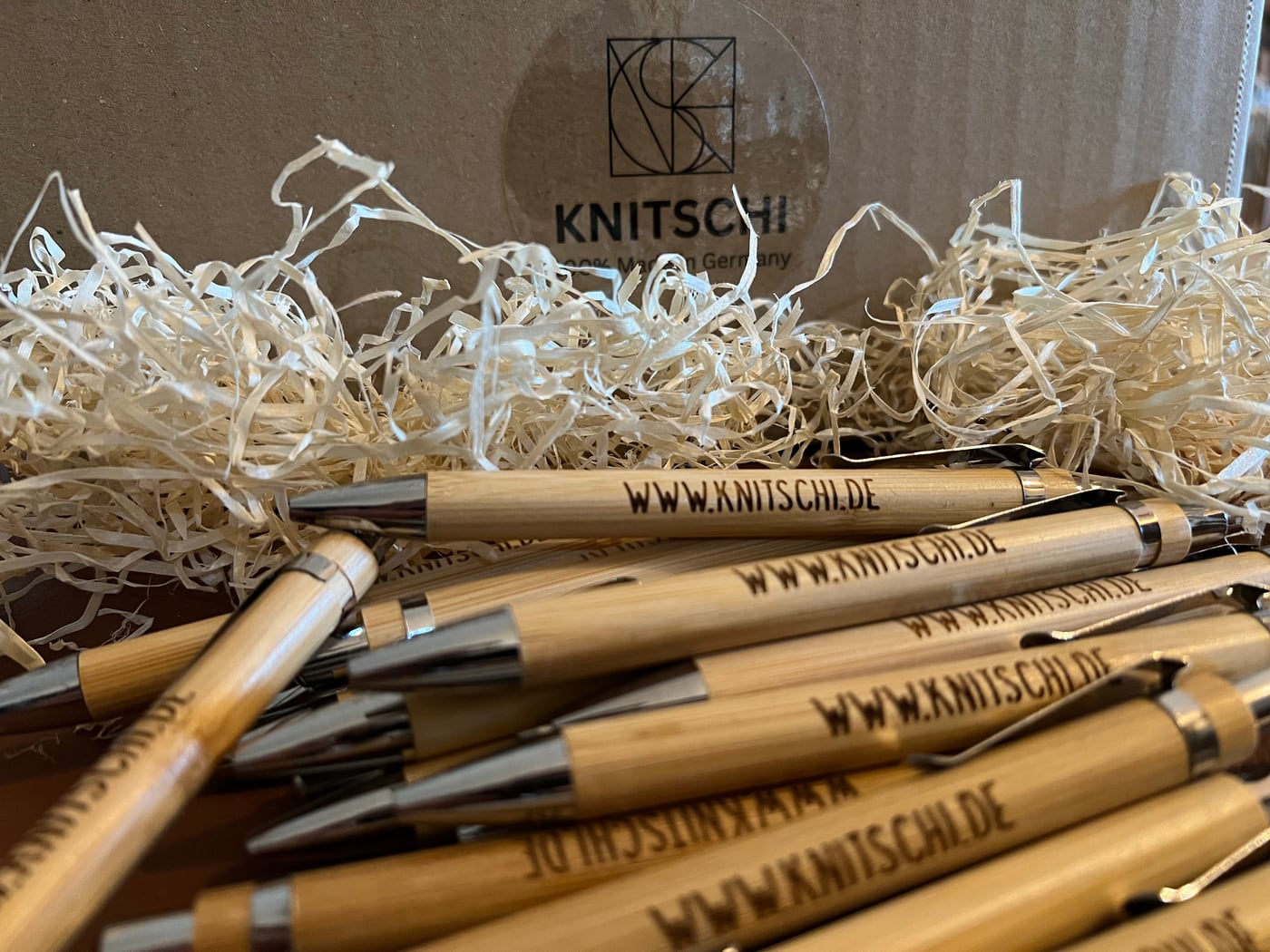 KNITSCHI wooden ballpoint pens in front of a box with brand print