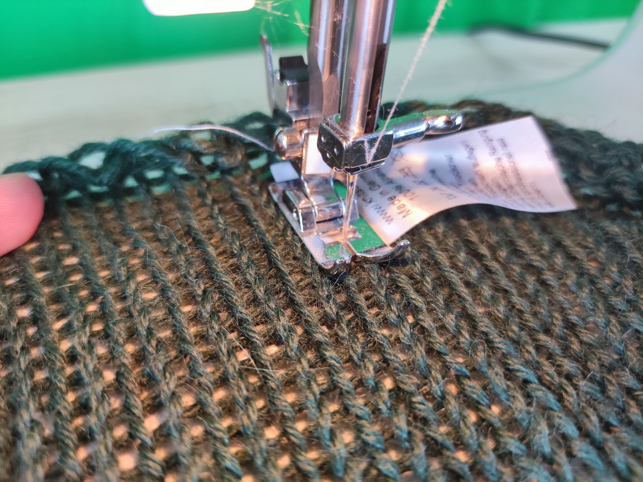 Pflegeetikett wird an einem KNITSCHI-Strickstück eingenäht