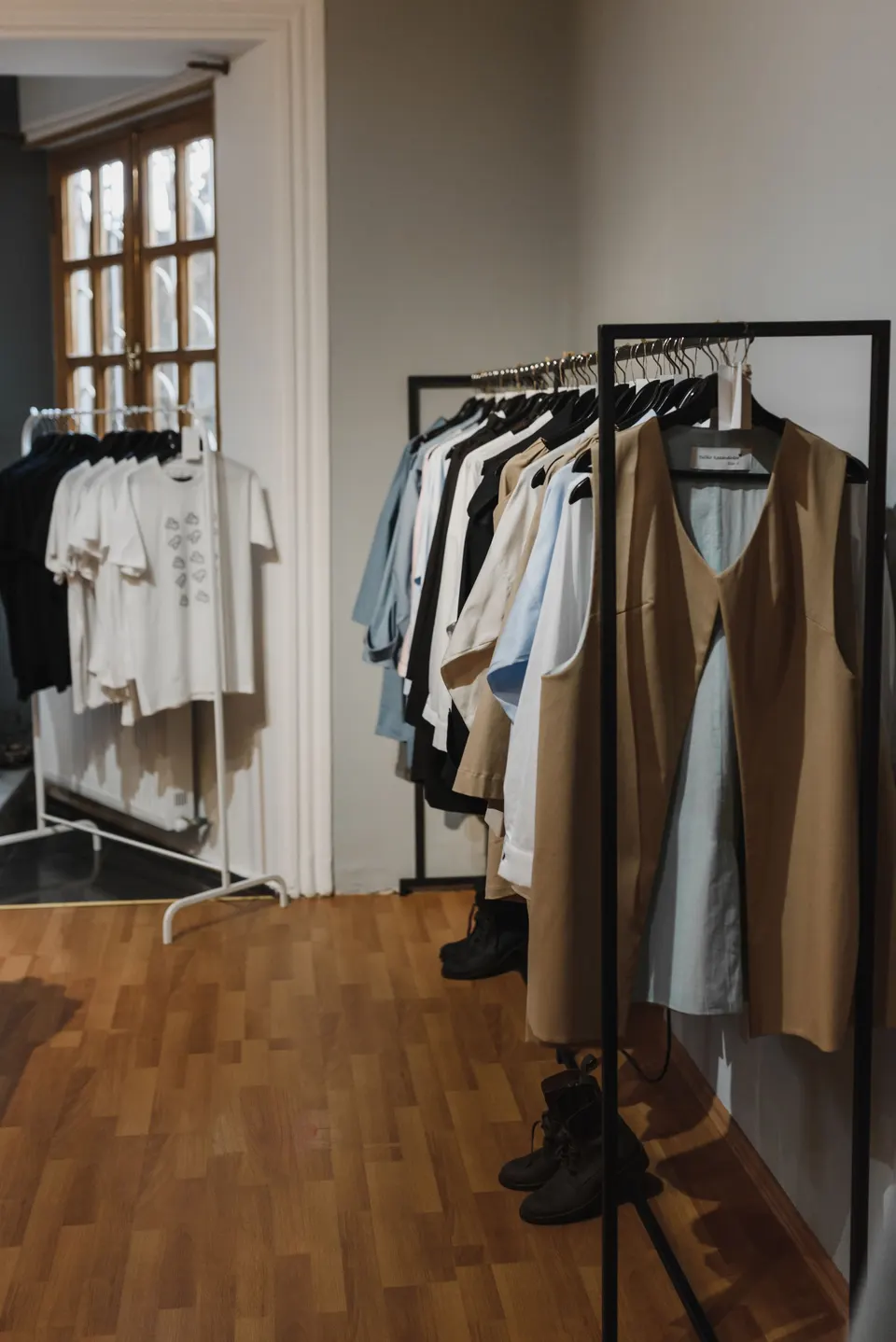 Reduziertes Boutique-Interieur mit ausgewählter Kleidung auf schwarzen Metallständern